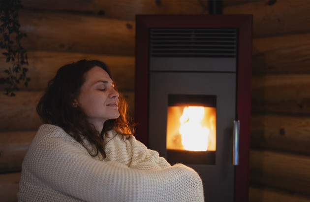Femme qui profite de la chaleur de son poêle a granulés