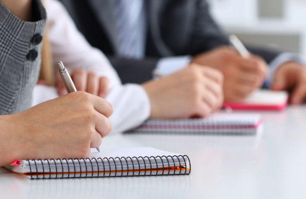 Plusieurs personnes qui prennent des notes sur leur carnet