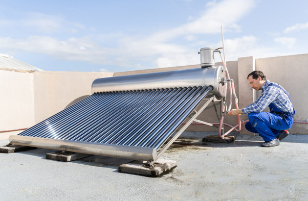 Artisan qui installe un chauffe eau solaire sur un toit