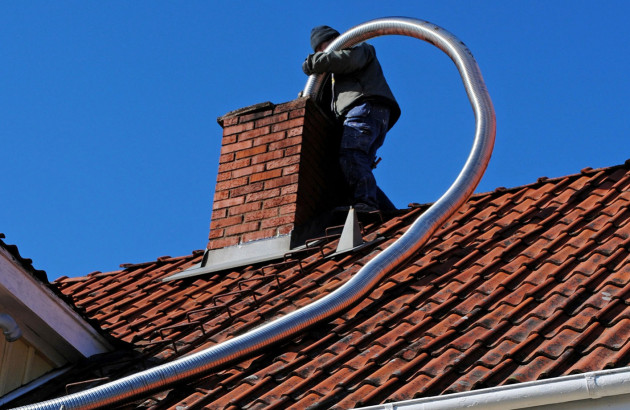 Ouvrier sur un toit qui insère un conduit de cheminée dans la cheminée