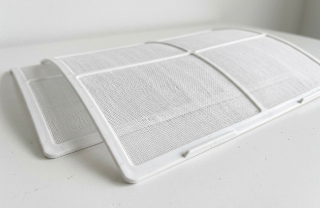 Filtre de climatiseur démonté prêt à être nettoyé pour assurer une bonne qualité d’air intérieur.