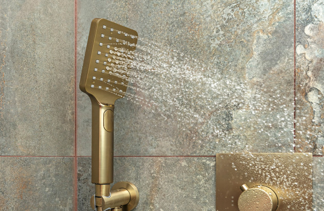 Pommeau de douche finition or brossé qui projette de l'eau
