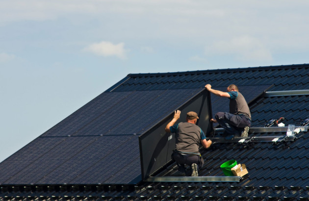 Deux professionnels qui installent des panneaux solaires sur un toit