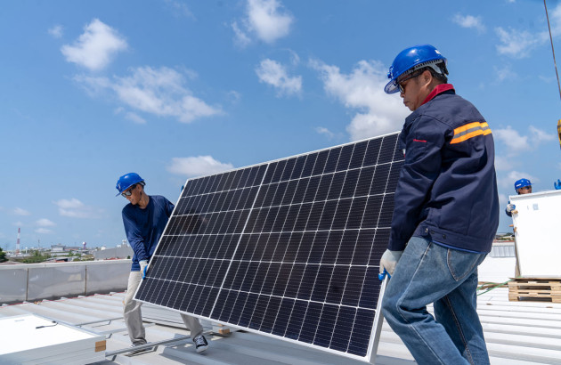 Deux professionnels installent un panneau solaire sur un toit d'immeuble