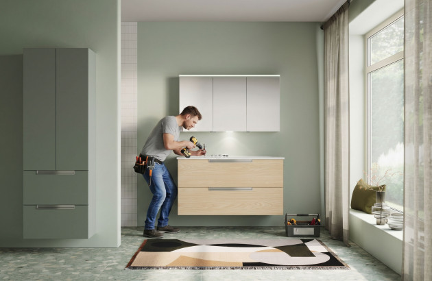 Artisan en train d’installer un meuble suspendu dans une salle de bains lumineuse au design scandinave.