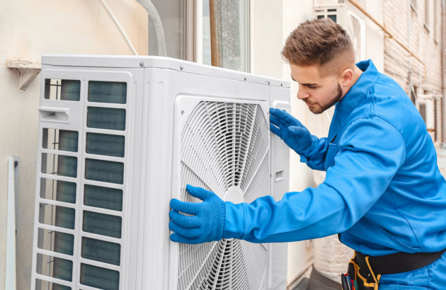 artisan qui installe un climatiseur unité extérieure