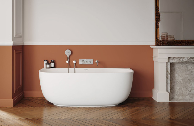Baignoire îlot blanche aux formes arrondies intégrée dans une salle de bains de style classique chic avec parquet et cheminée.
