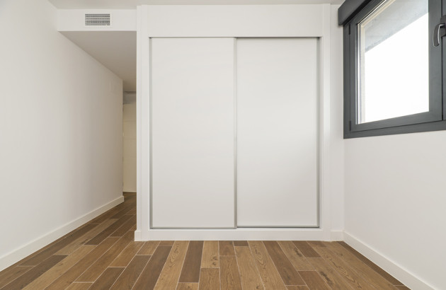  Intérieur de pièce moderne avec un plancher en bois et armoire blanche à portes coulissantes et une climatisation gainable en haut du mur