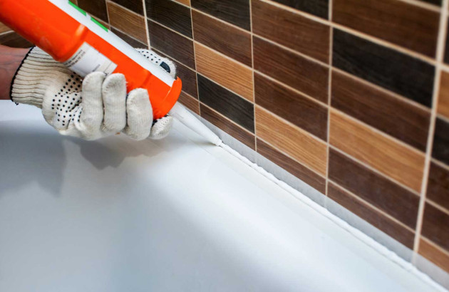 Personne qui applique des joints de salle de bains anti-moisissure