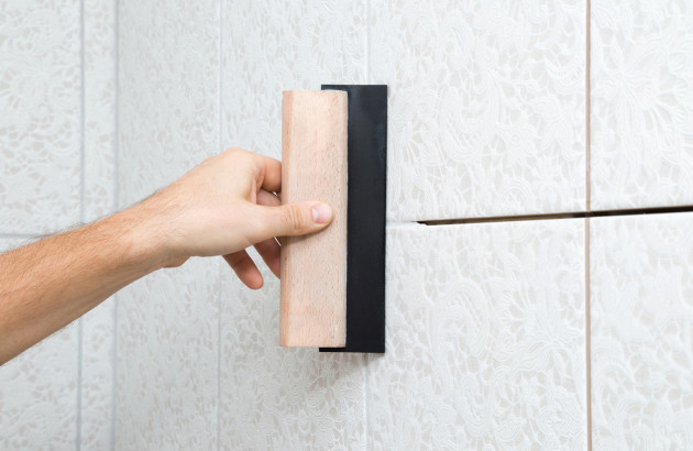 Personne qui réalise les joints de carrelage de sa salle de bains