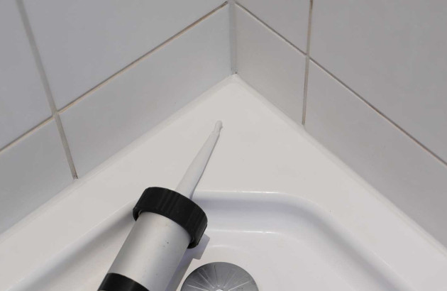 Personne qui refait les joints de sa salle de bains en silicone ou acrylique