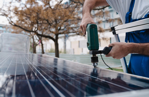 Artisan qui utilise un outil pour fixer des panneaux solaires