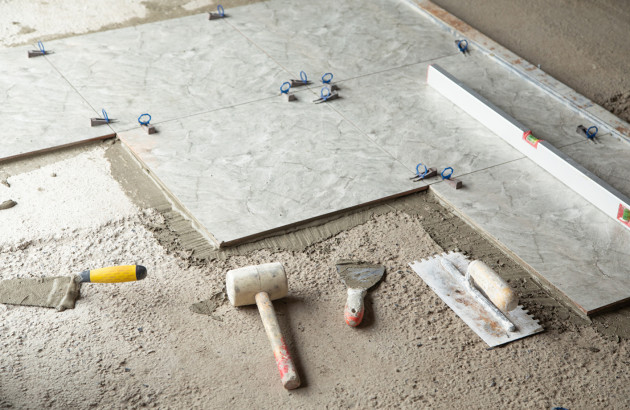Chantier de carrelage  avec outillage et carreaux posés au sol