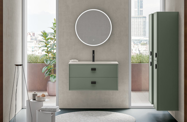 Meuble vasque suspendu vert avec deux tiroirs, miroir rond lumineux et colonne de rangement assortie.
