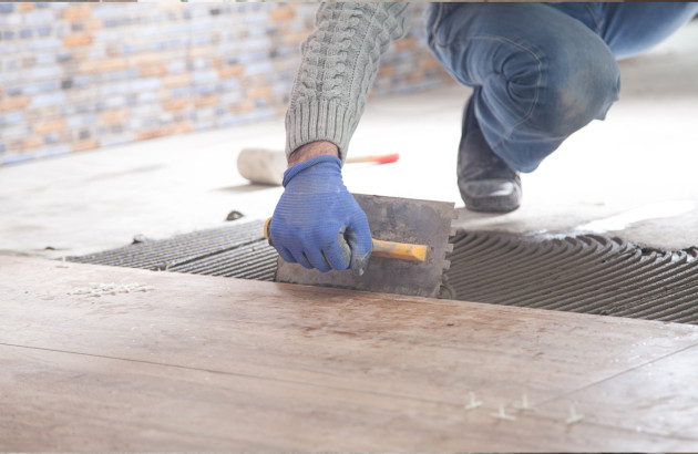 Homme qui applique du mortier colle sur des carreaux de carrelage