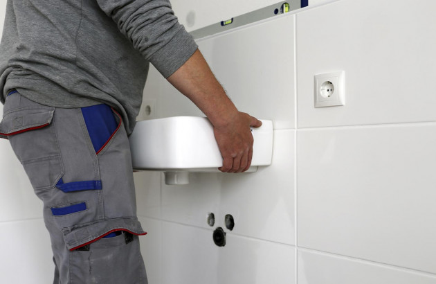 Professionnel en train de poser un lave-mains dans des WC