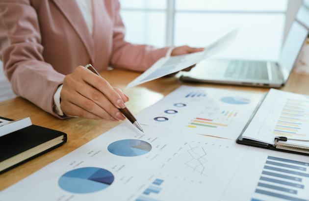 Analyse de consommation énergétique : main pointant des graphiques et tableaux de performance.