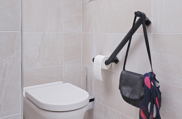 WC suspendu avec barre d’appui murale noire pour l’accessibilité et la sécurité.