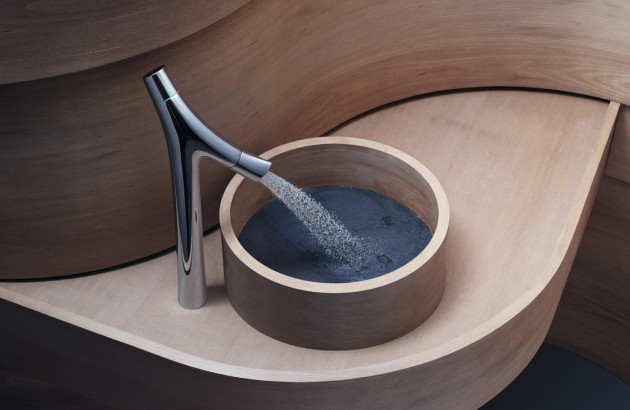 Mitigeur haut de gamme avec jet en microgouttelettes alimentant une vasque ronde intégrée dans un meuble en bois sculpté.