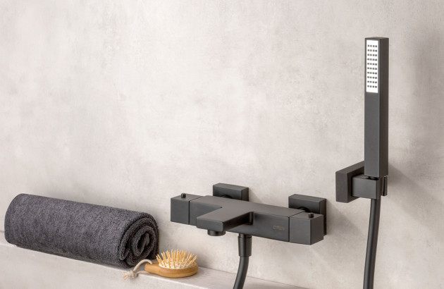 Robinet de salle de bains noir mat posé sur un meuble en bois clair avec vasque blanche contemporaine.