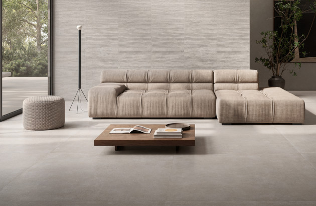 Salon minimaliste avec carrelage beige mat grand format et canapé modulable dans une ambiance naturelle.