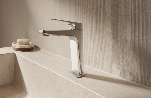 Mitigeur de lavabo chromé au design moderne installé sur une vasque beige.