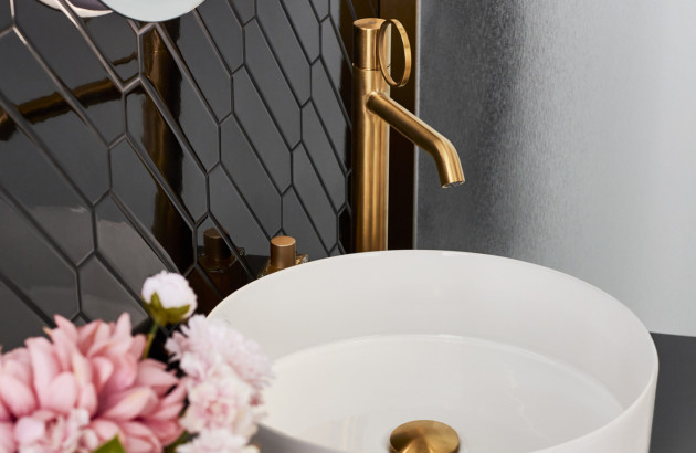 Lavabo avec un mitigeur or brossé et une fleur rose