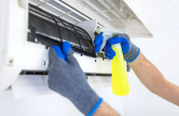 Professionnel pulvérisant un produit nettoyant sur les filtres d’une climatisation