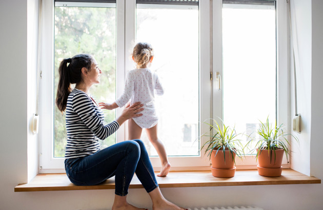 Femme et sa fille qui sont sur le rebord d'une fenêtre, pieds sur le radiateur
