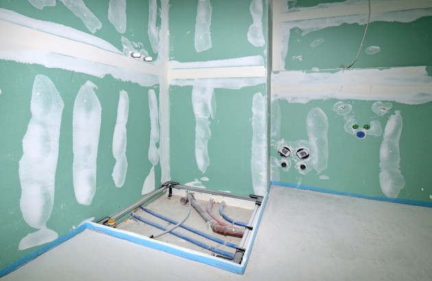 Salle de bains en cours de rénovation avec arrivée d’eau et emplacement de douche avant finition.