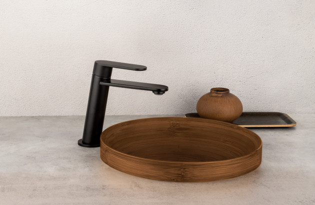 Mitigeur de lavabo noir mat associé à une vasque ronde effet bois.