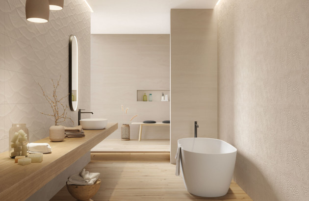 Salle de bains haut de gamme avec baignoire îlot, textures murales et ambiance naturelle apaisante.