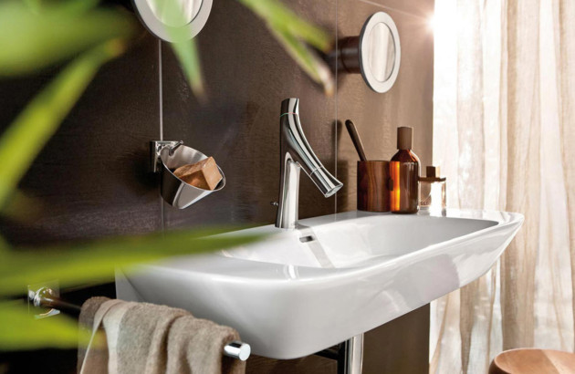 Robinet design chromé installé sur une vasque blanche dans une salle de bains chaleureuse aux accents boisés.