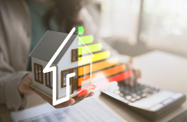 Femme qui tient une maquette de maison avec un DPE et qui utilise une calculatrice