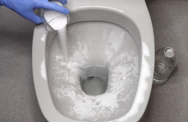 Personne qui verse une solution naturelle pour détartrer les toilettes