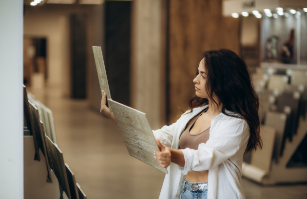 Cliente dans un magasin de carrelage comparant de grands échantillons pour choisir le bon revêtement 