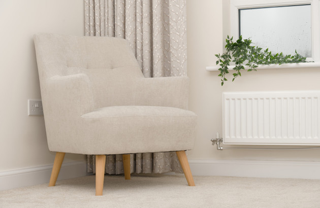 Fauteuil dans un coin d'un salon avec un radiateur installé sous une fenêtre
