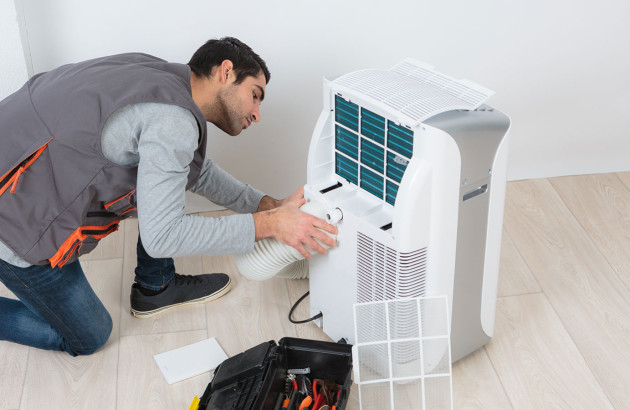Homme qui intervient sur un climatiseur mobile