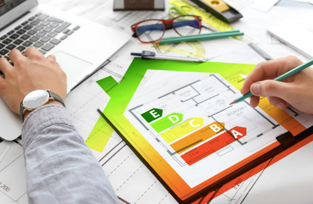 Plan de maison sur bureau avec ordinateur, graphiques et étiquette énergie, pour estimer la performance énergétique.