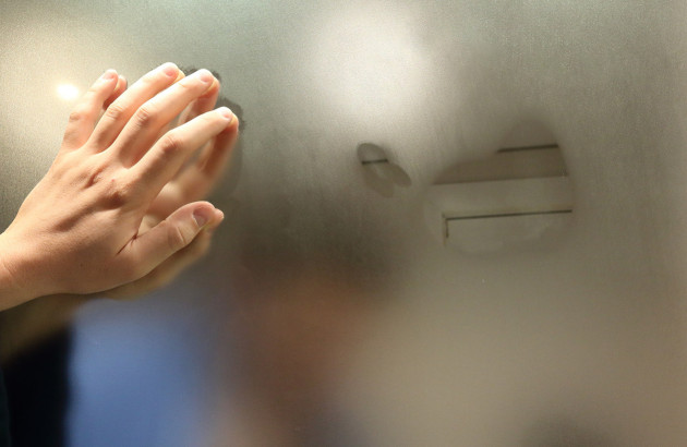 Main qui fait des traces de buée sur une vitre de salle de bains