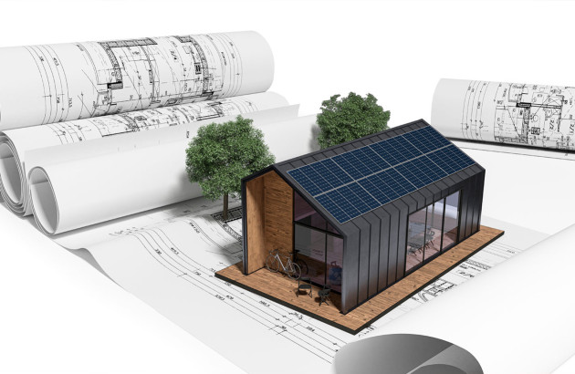 Maquette de maison avec des panneaux photovoltaïques posée sur des plans de construction