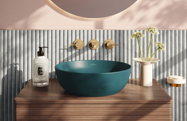 Vasque à poser bleu profond associée à une robinetterie dorée et un meuble en bois.