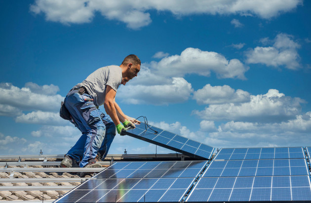 Hommes qui installent des panneaux solaires sur le toit d'une maison