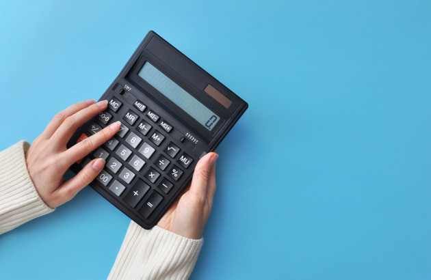 quelqu'un qui tient une calculatrice noire sur un fond bleu uni 