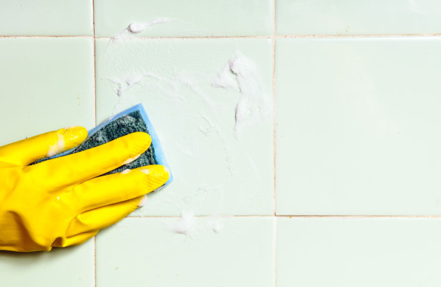 Gant jaune qui nettoie des carreaux de carrelage muraux