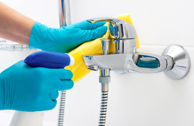 Personne qui nettoie son mitigeur de douche avec des produits naturels et des gants