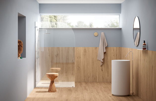 Salle de bains scandinave avec douche à l’italienne, panneaux effet bois et vasque sur colonne.