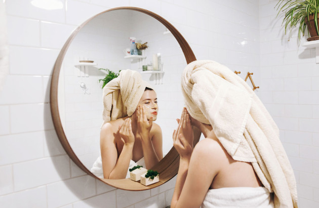 Femme qui se maquille devant son miroir avec un cadre en bois