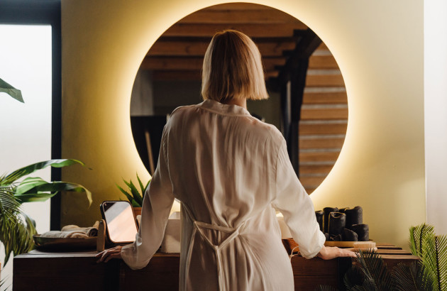 Femme de dos qui se regarde dans son miroir éclairé