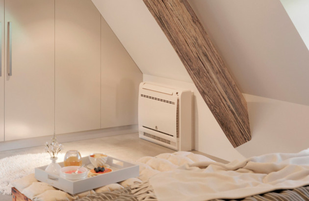 Climatisation console installée dans une chambre mansardée sous poutres apparentes.